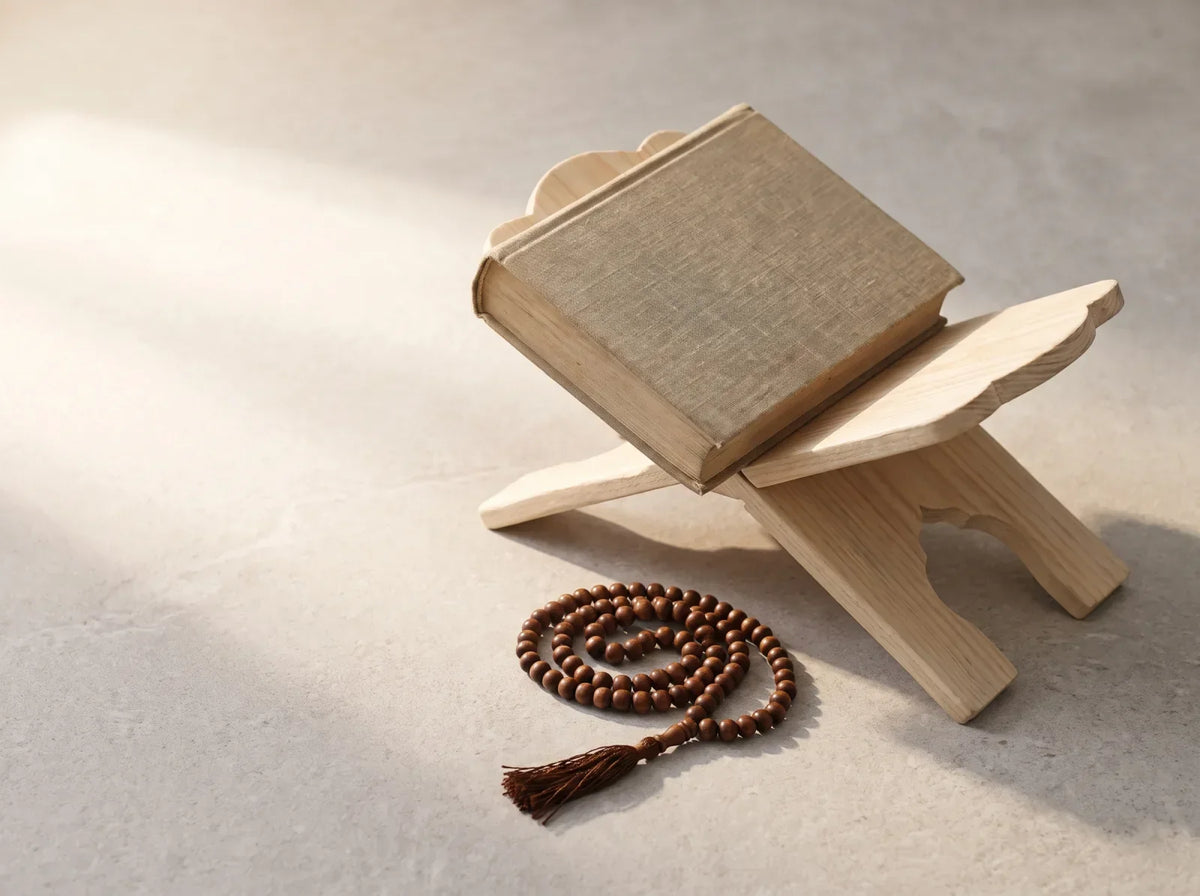 A cloth-bound book on a carved wooden stand beside wooden prayer beads