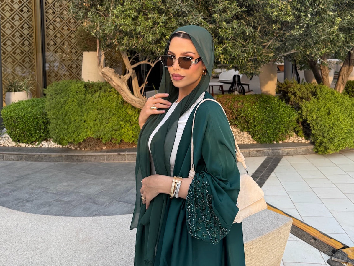 A woman wearing an emerald green Maryam abaya from Fajr Noor