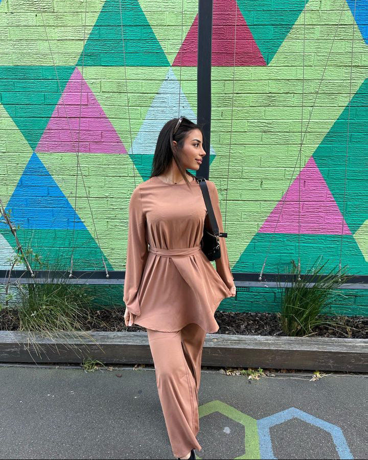 Woman in a beige outfit standing in front of a colorful geometric mural.