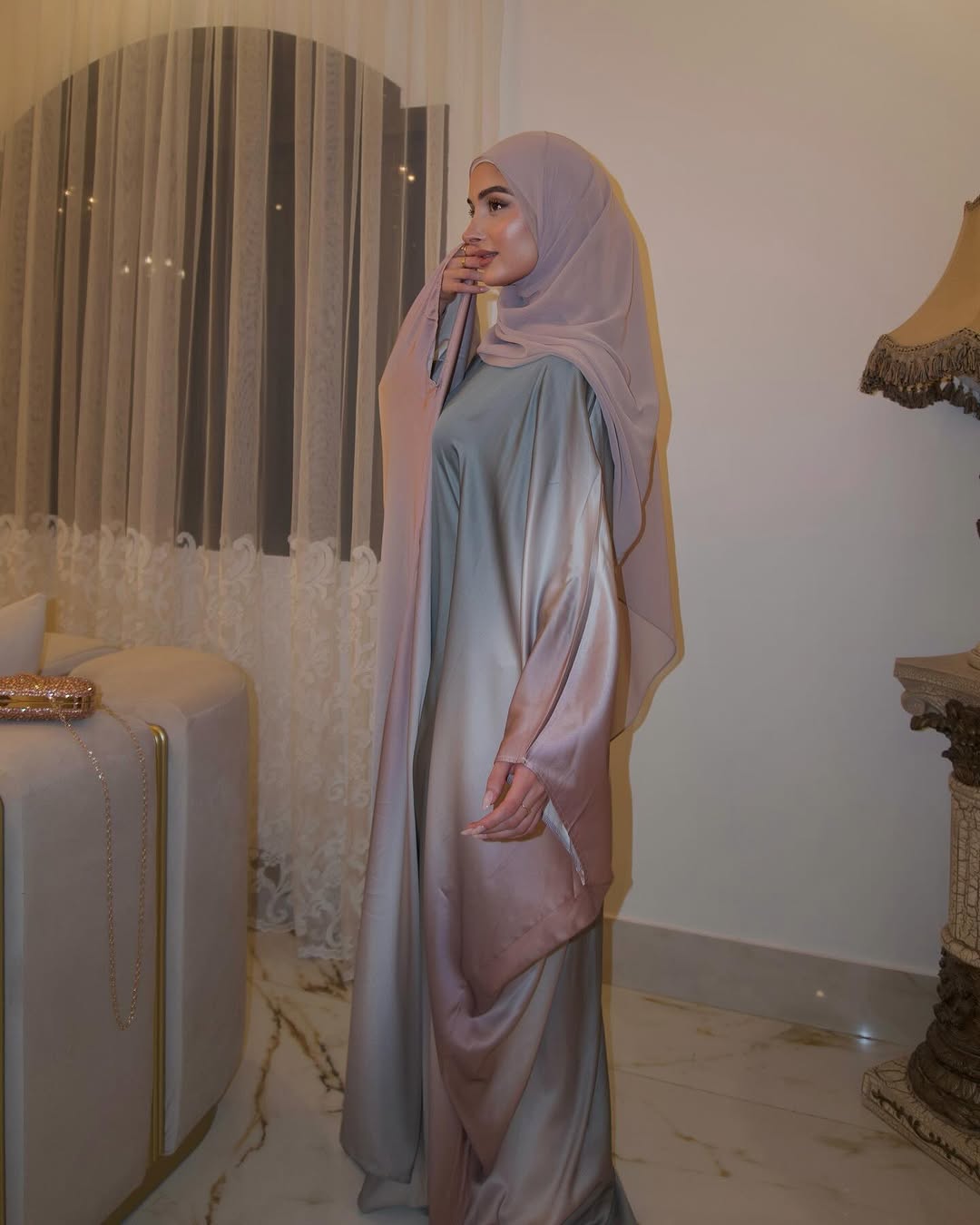 Woman in a light blue and pink traditional outfit standing in a decorated room.