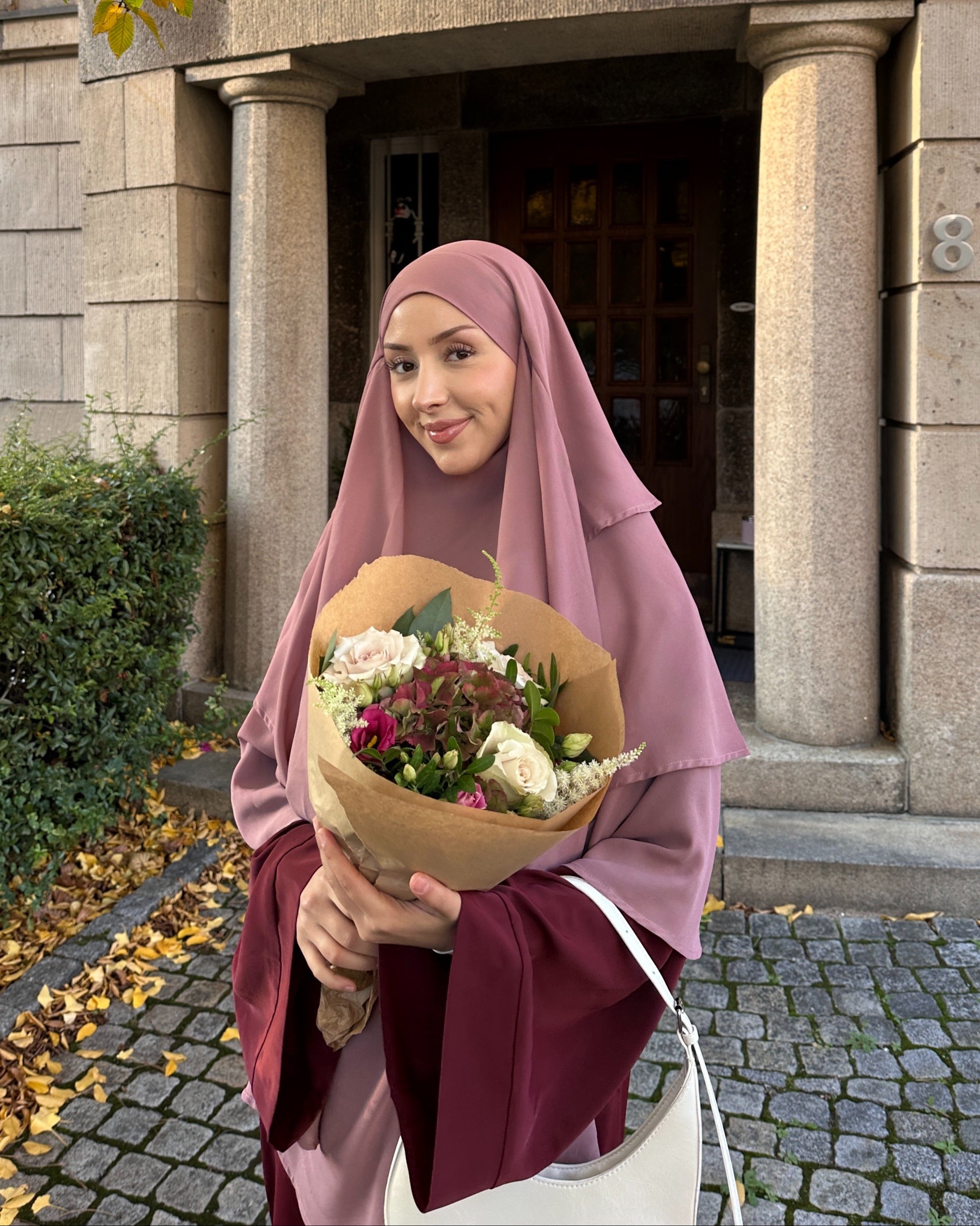 Woman holding a bouquet of flowers in front of a stone building