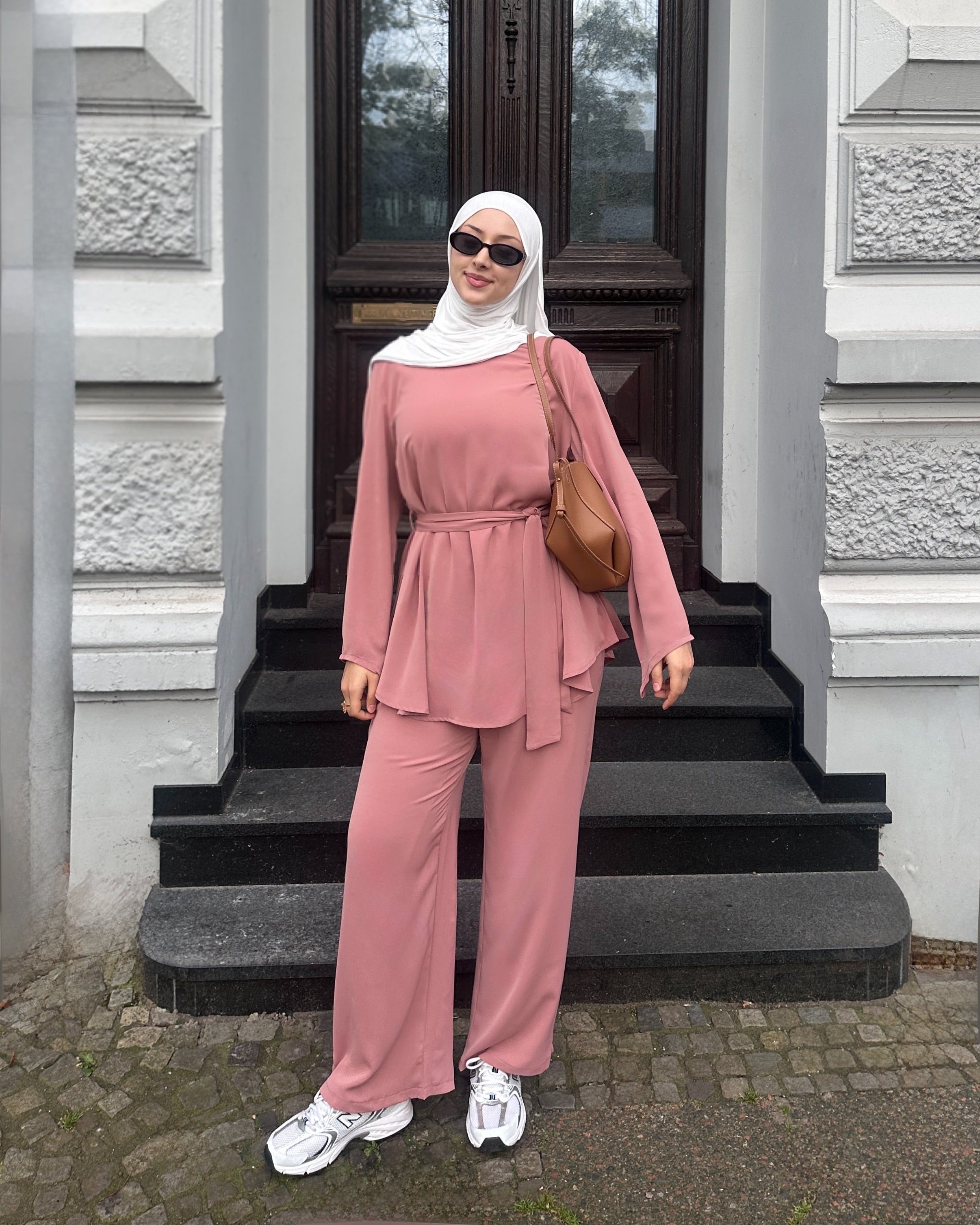 Woman in a pink outfit standing on steps outside a building