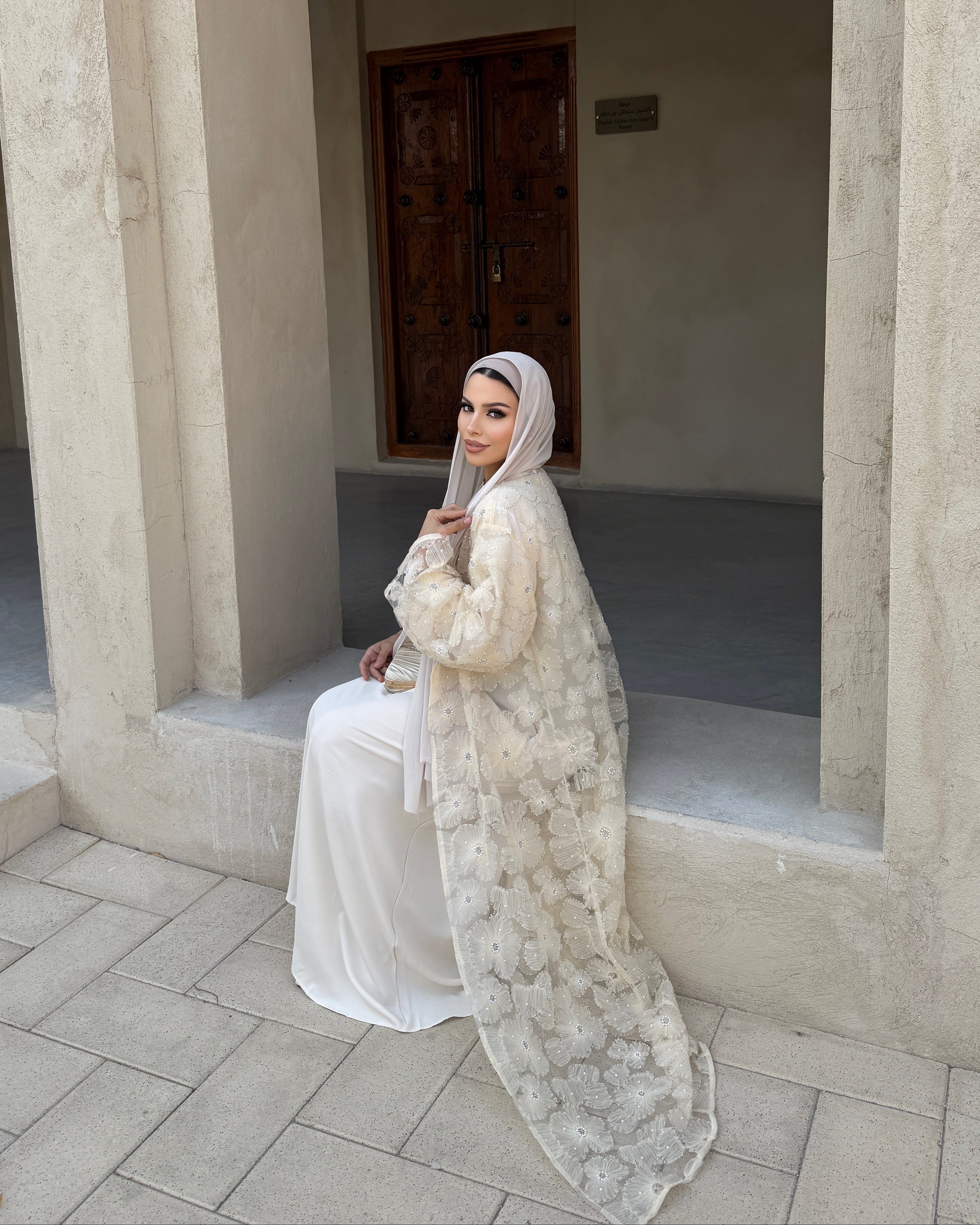 Woman in a white dress sitting in a stone archway