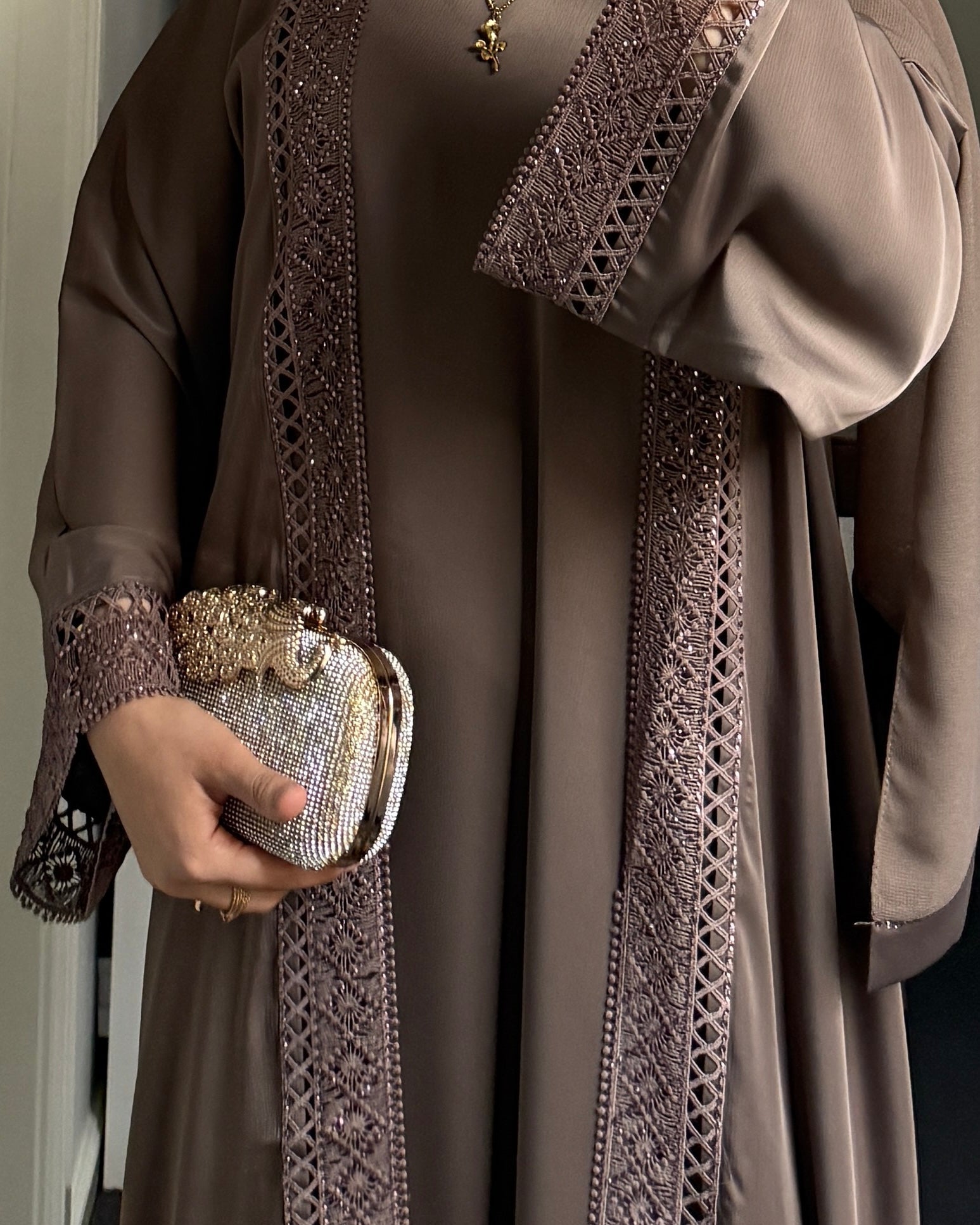 Person wearing a detailed brown dress holding a matching handbag.
