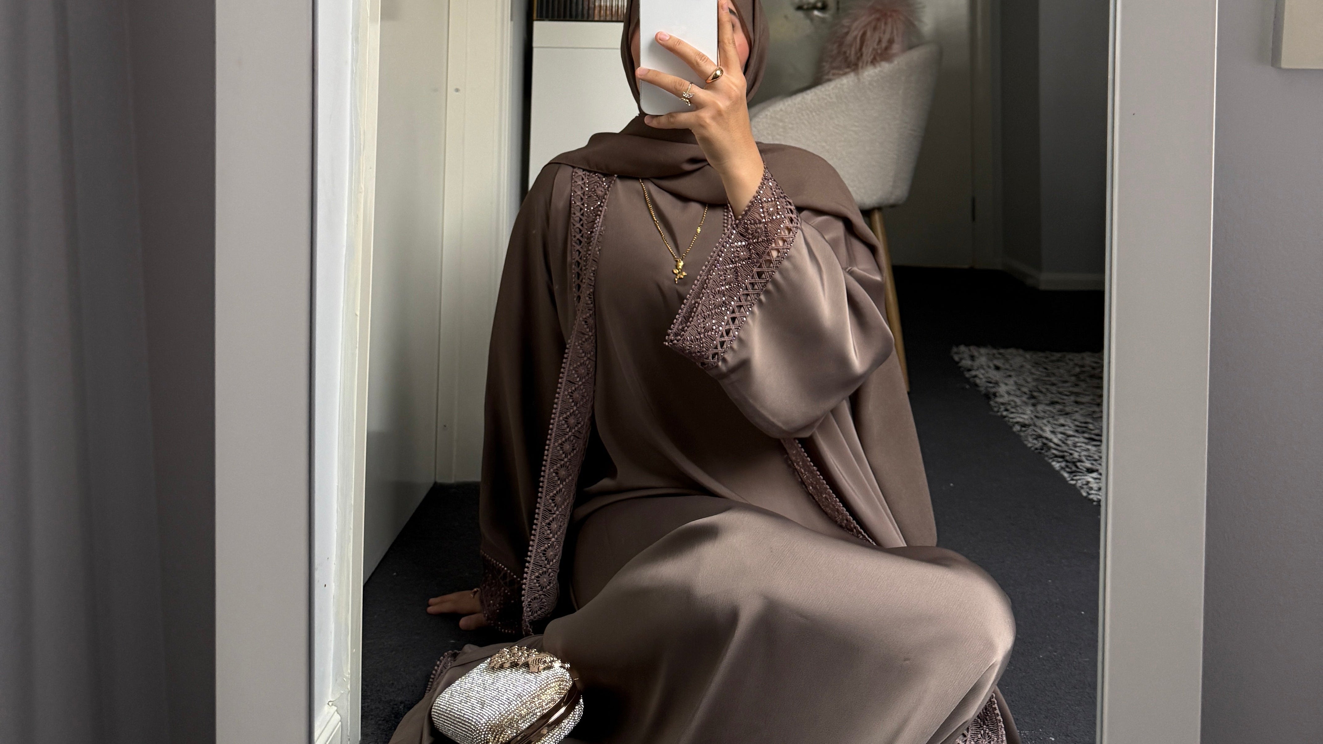 Person in a brown eid outfit taking a mirror selfie in a room.