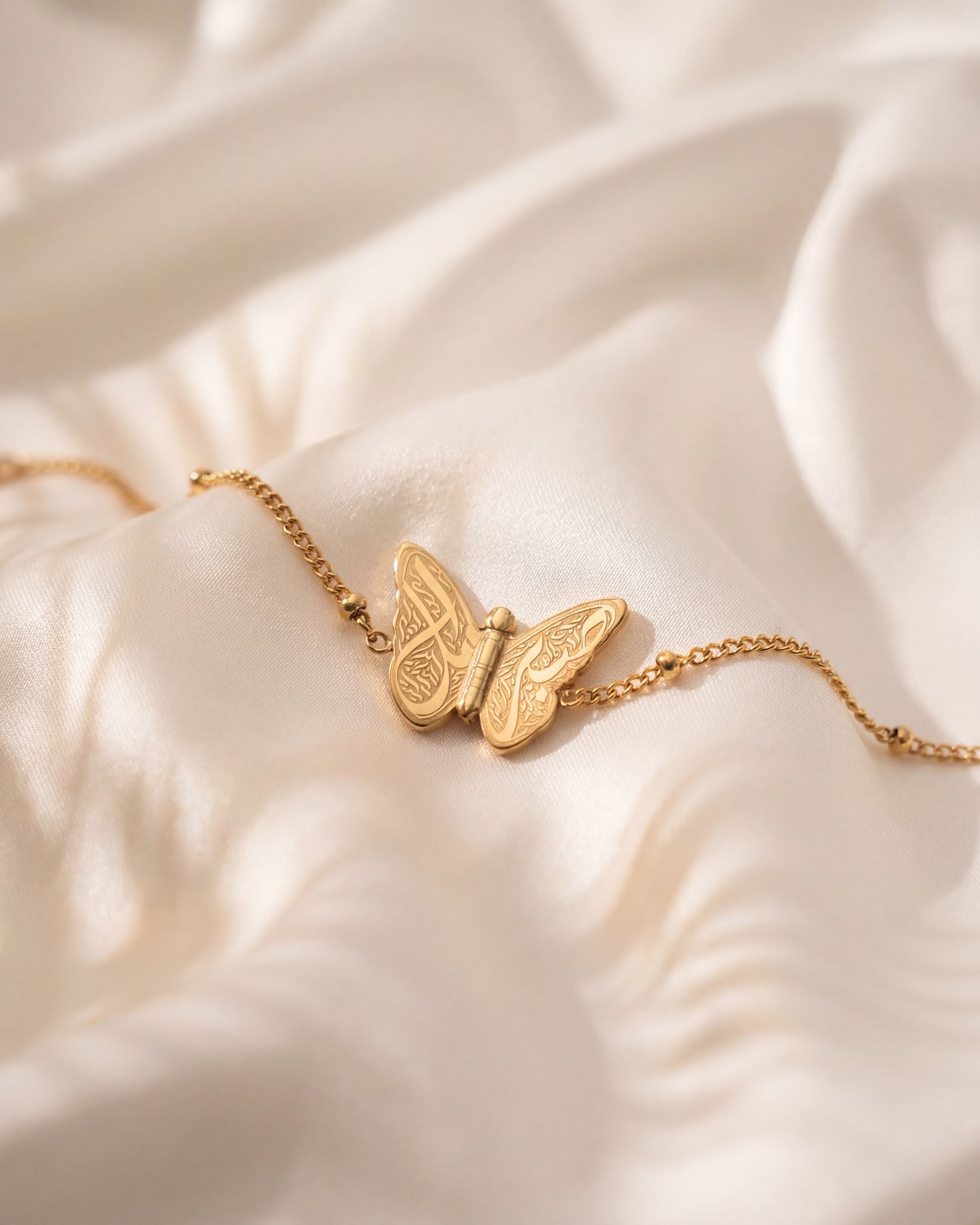 Gold butterfly bracelet on a soft beige fabric background