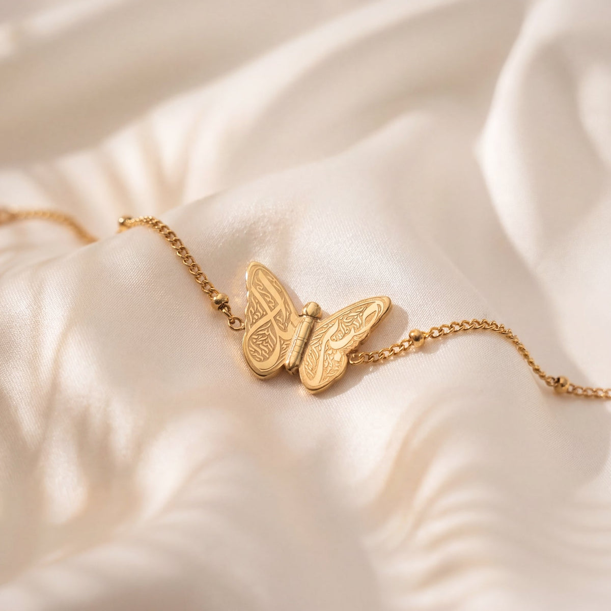 Gold butterfly bracelet on a soft beige fabric background