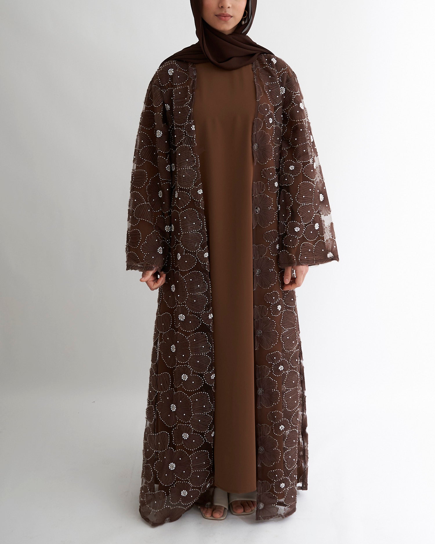 Woman wearing a brown floral abaya on a white background