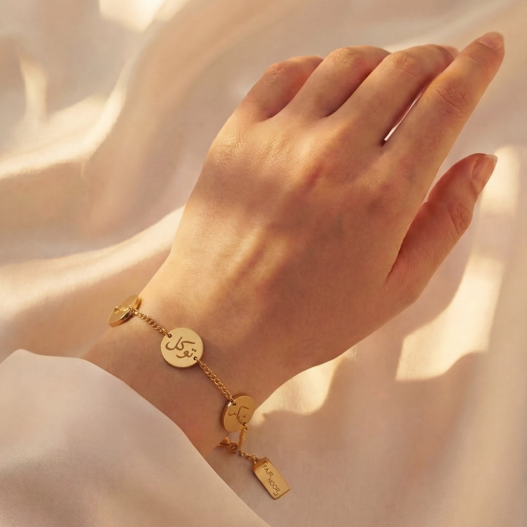 Gold bracelet on a hand against a soft beige background