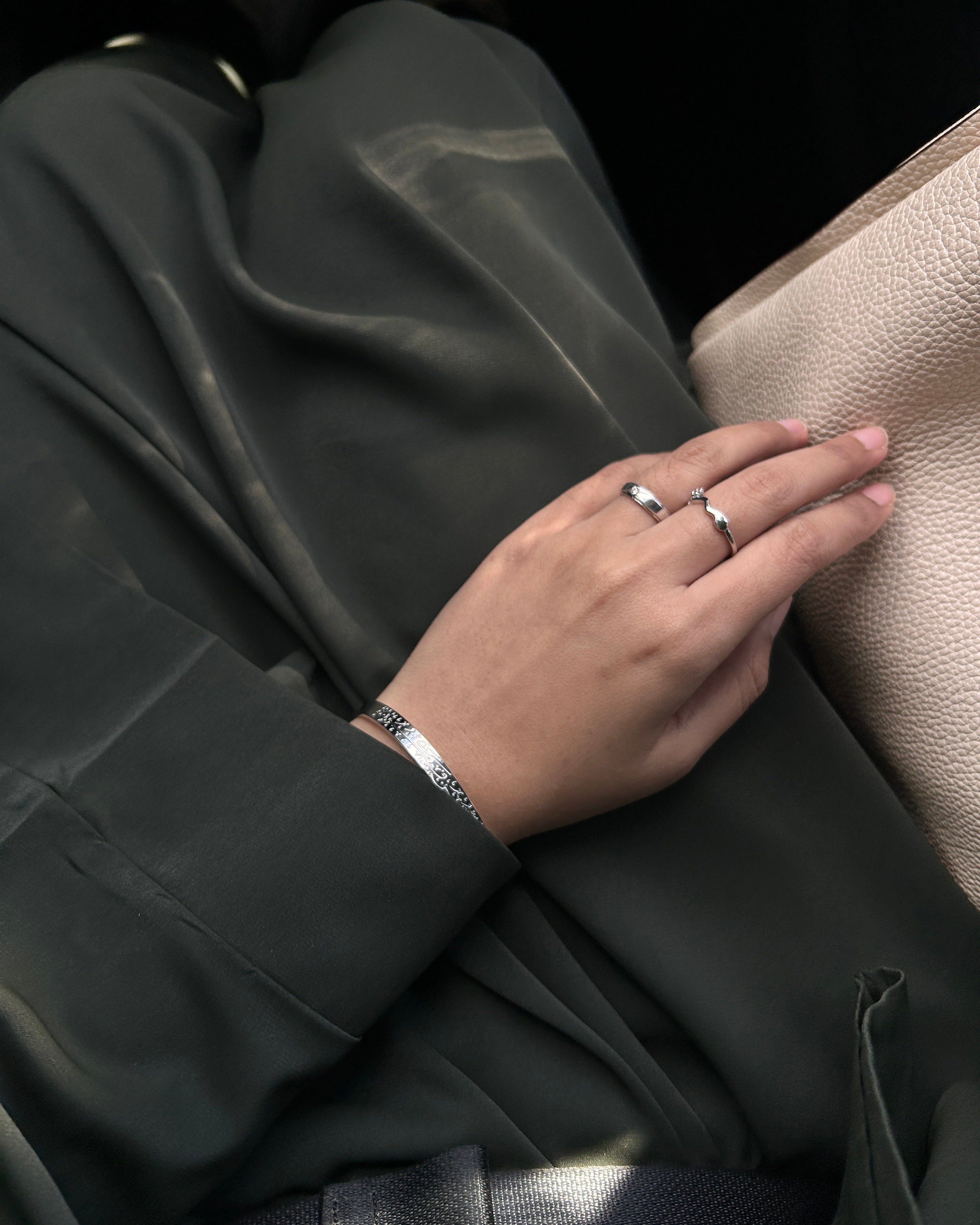 Close-up of a hand with rings on a textured surface