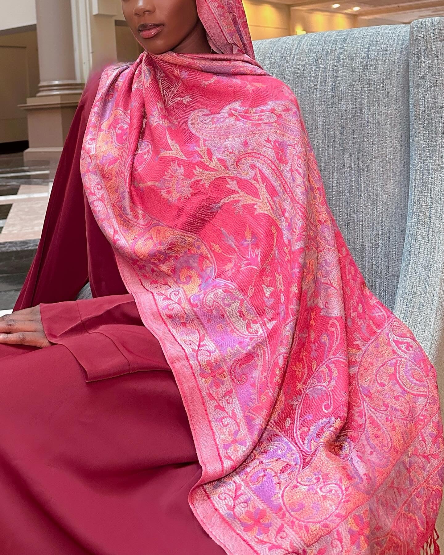 Person wearing a pink hijab with floral patterns in an indoor setting