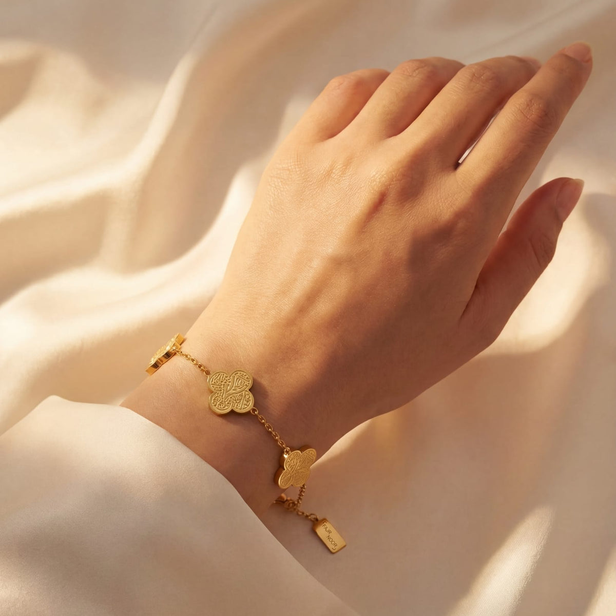 Gold bracelet on a hand against a soft beige background