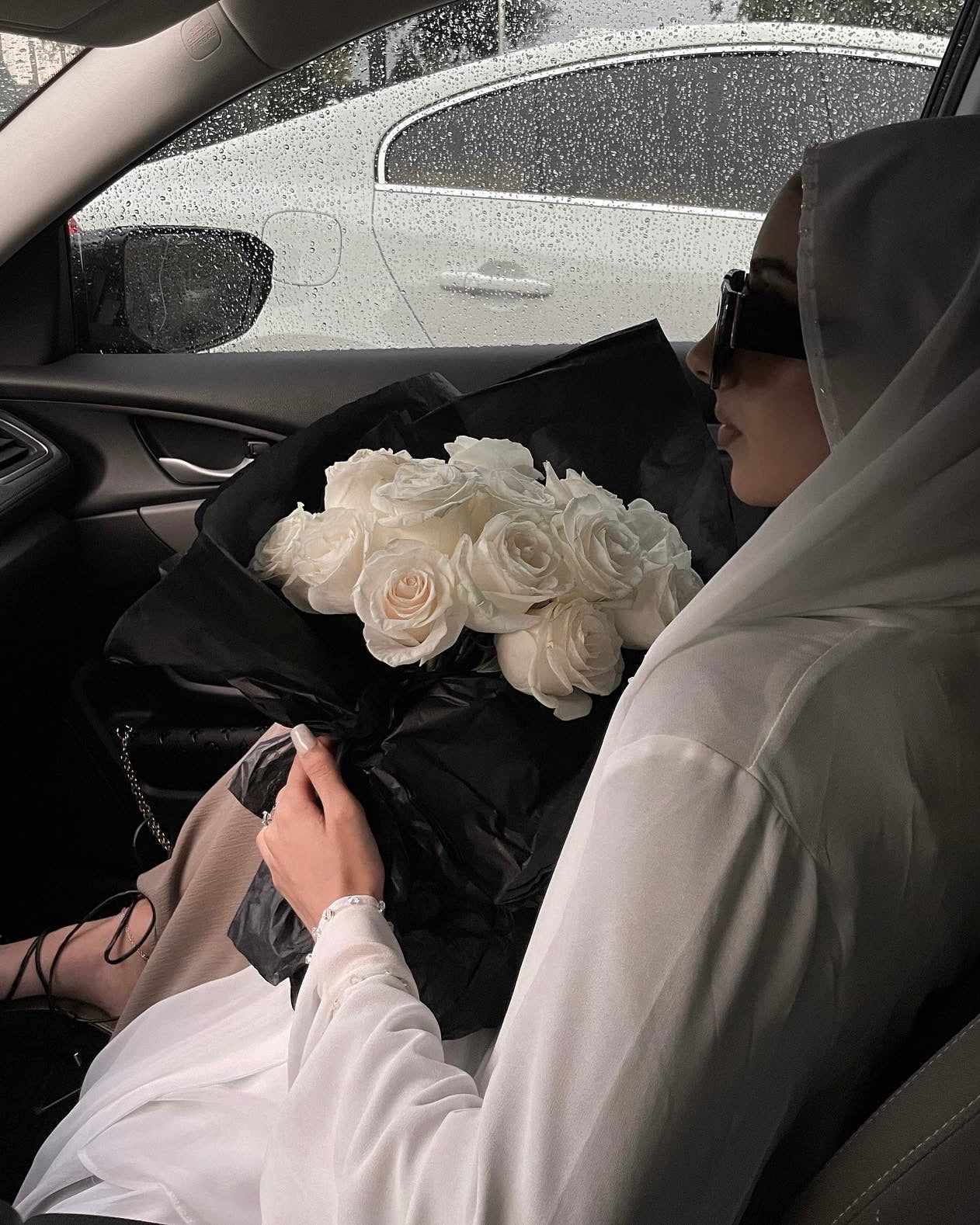 Person in a car holding a bouquet of white roses