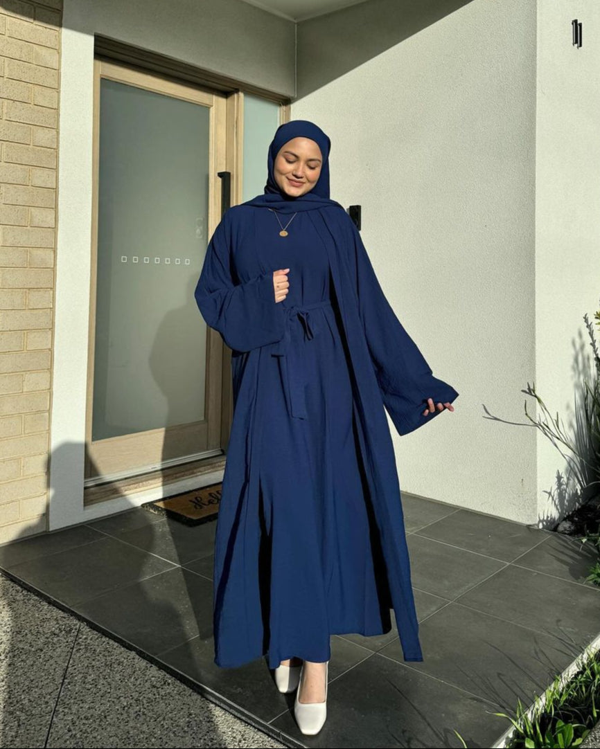 Woman in a blue abaya standing outside a modern building