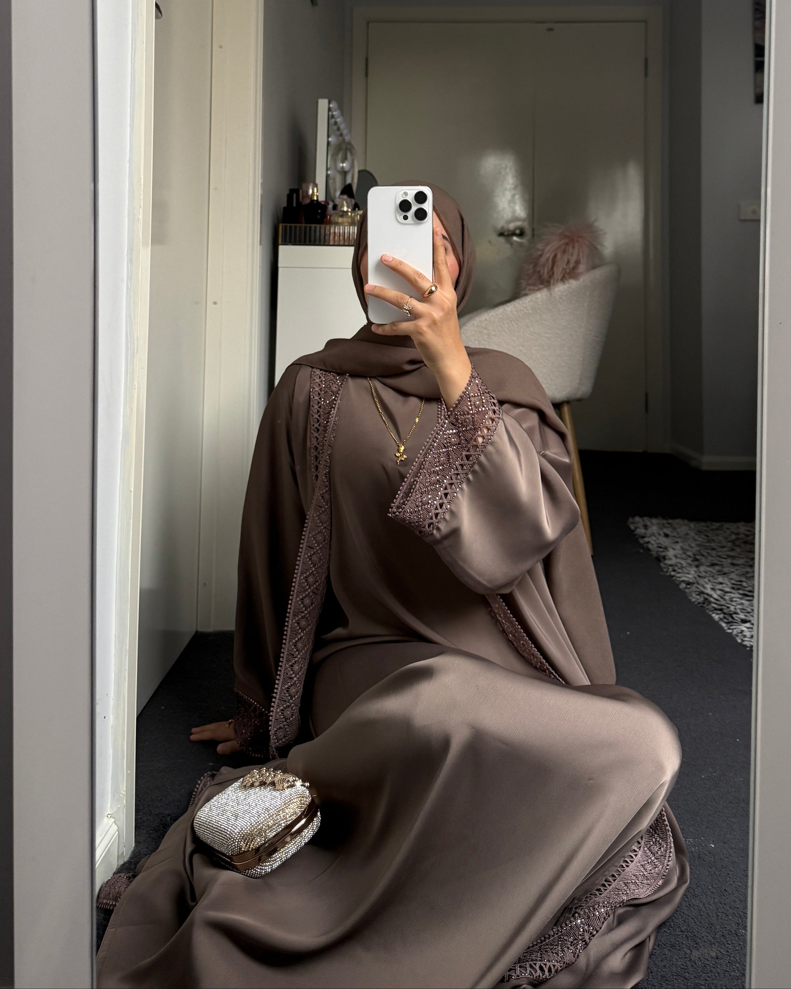 Person in a brown eid outfit taking a mirror selfie in a room.