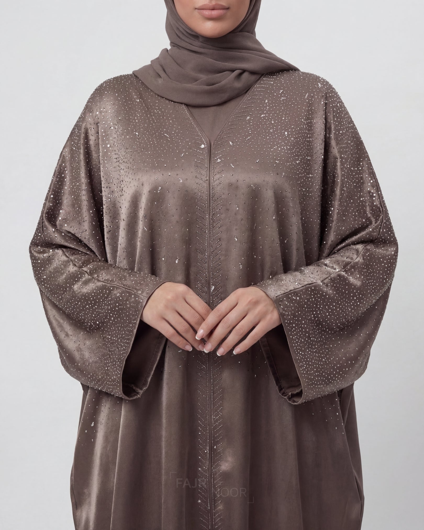 Brown abaya with glittery details on a plain background