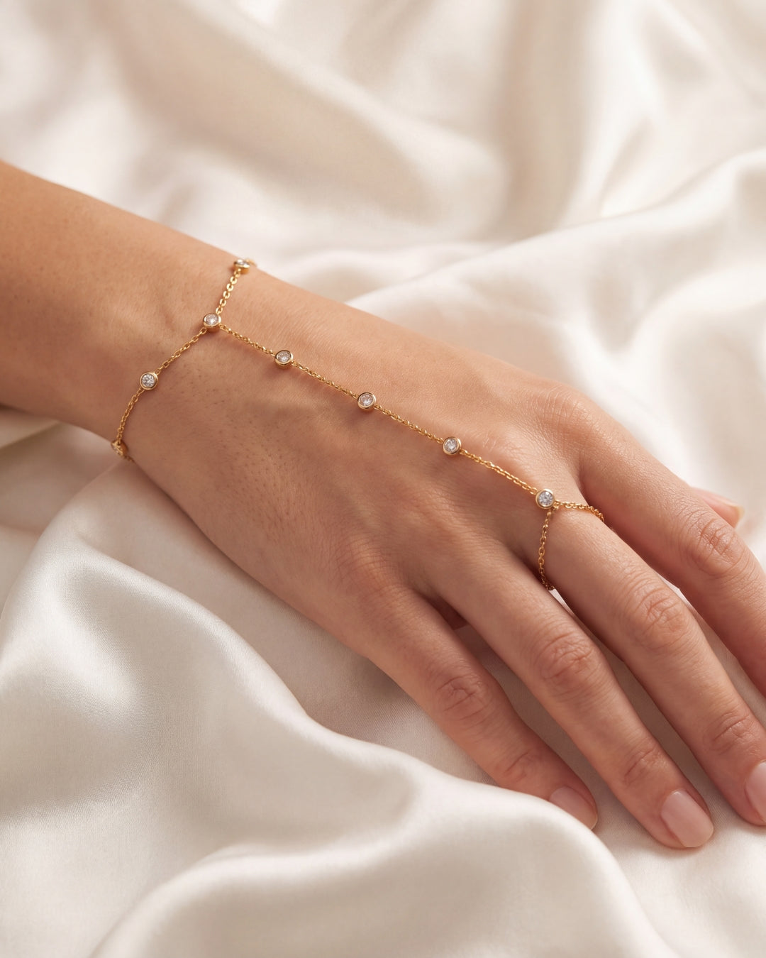 Woman's hand wearing a delicate gold hand chain bracelet with finger ring