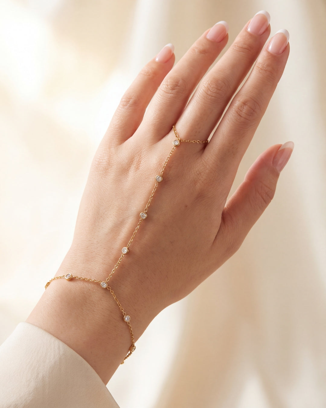 Woman's hand wearing a delicate gold hand chain bracelet with finger ring