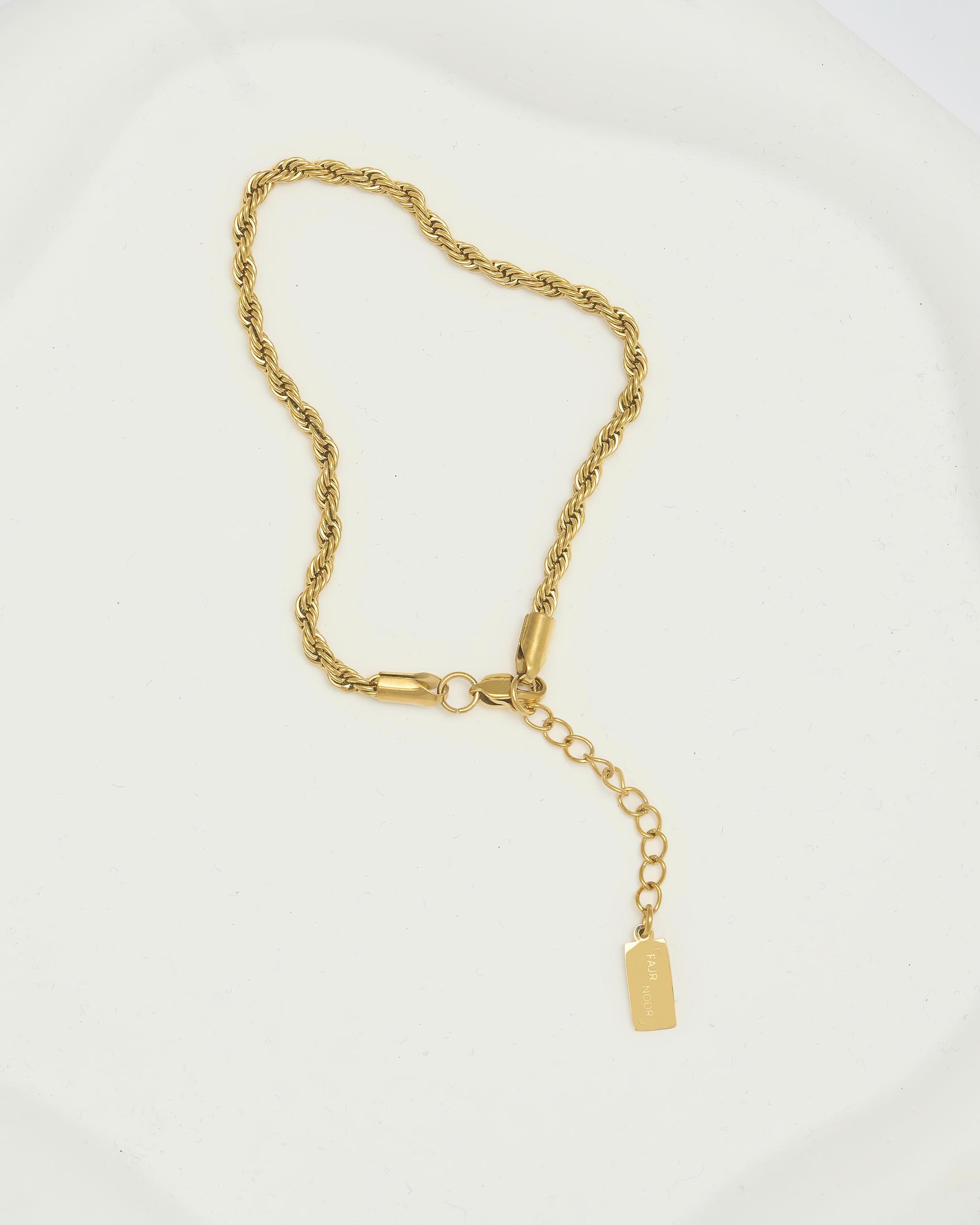 Gold chain bracelet with a tag on a white background