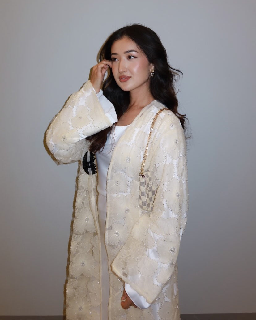 Woman wearing a light-colored traditional outfit against a plain background