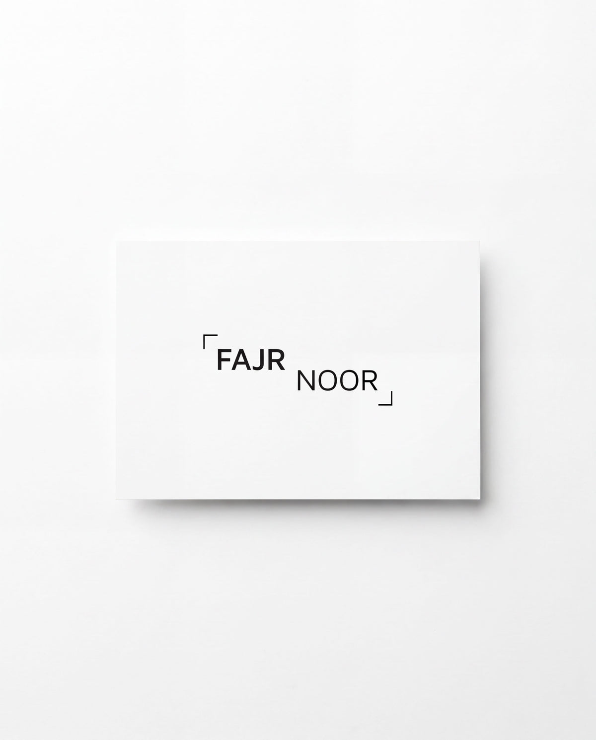 A minimalist white rectangular card or print with the text '“FAJR NOOR” in black sans-serif lettering, centered on a clean white background.