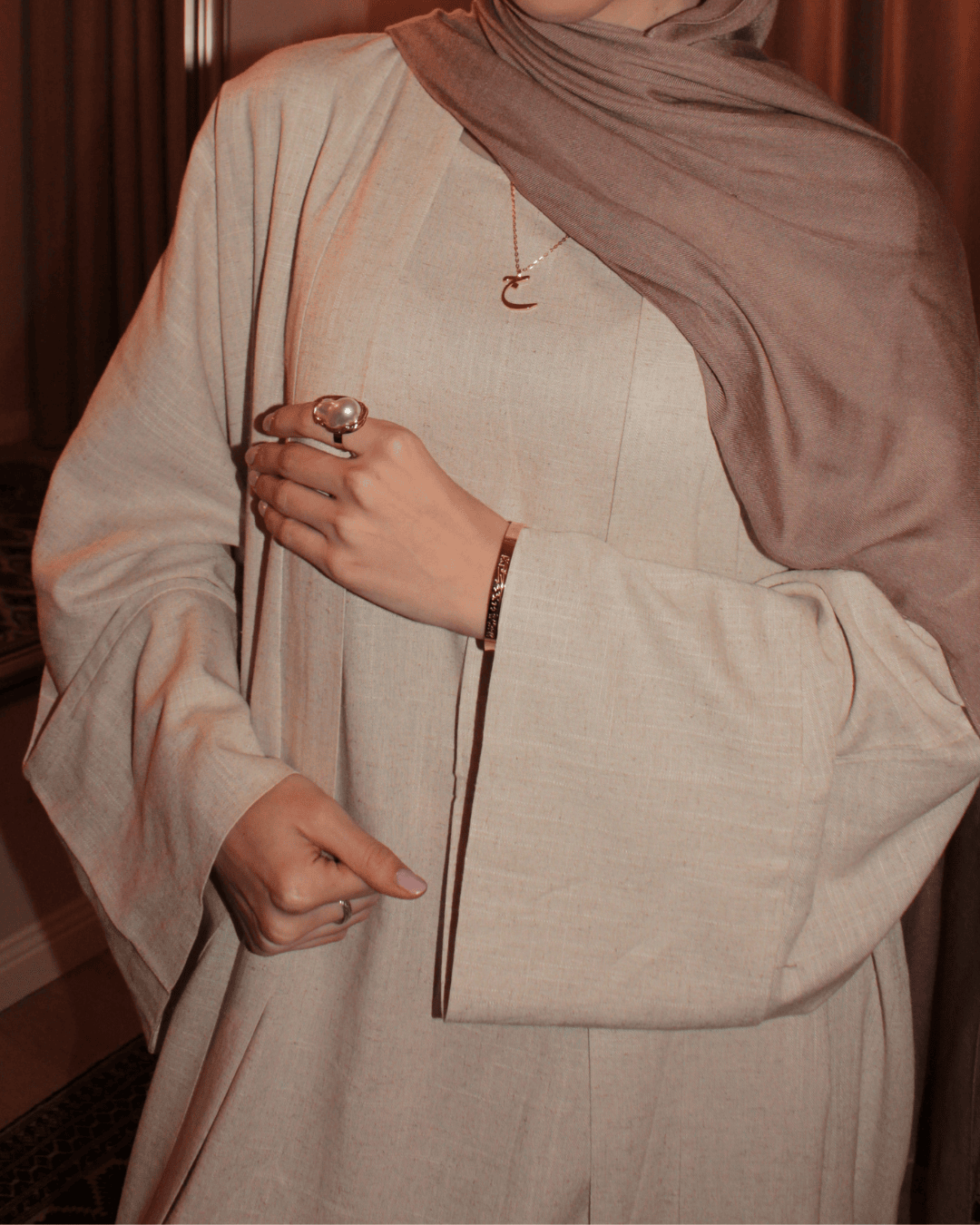 Person wearing a beige outfit with a brown hijab indoors