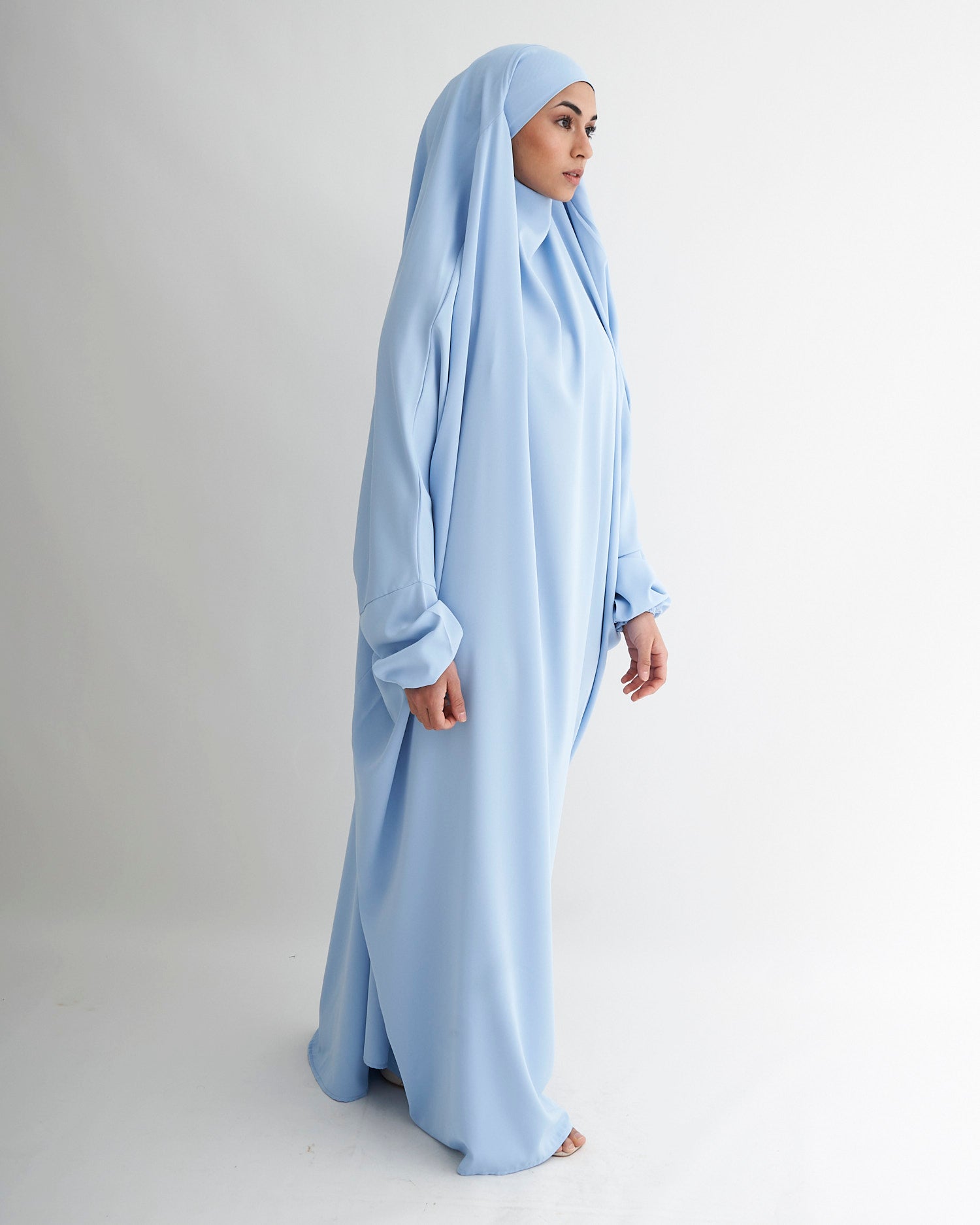 Woman wearing a light blue abaya on a white background