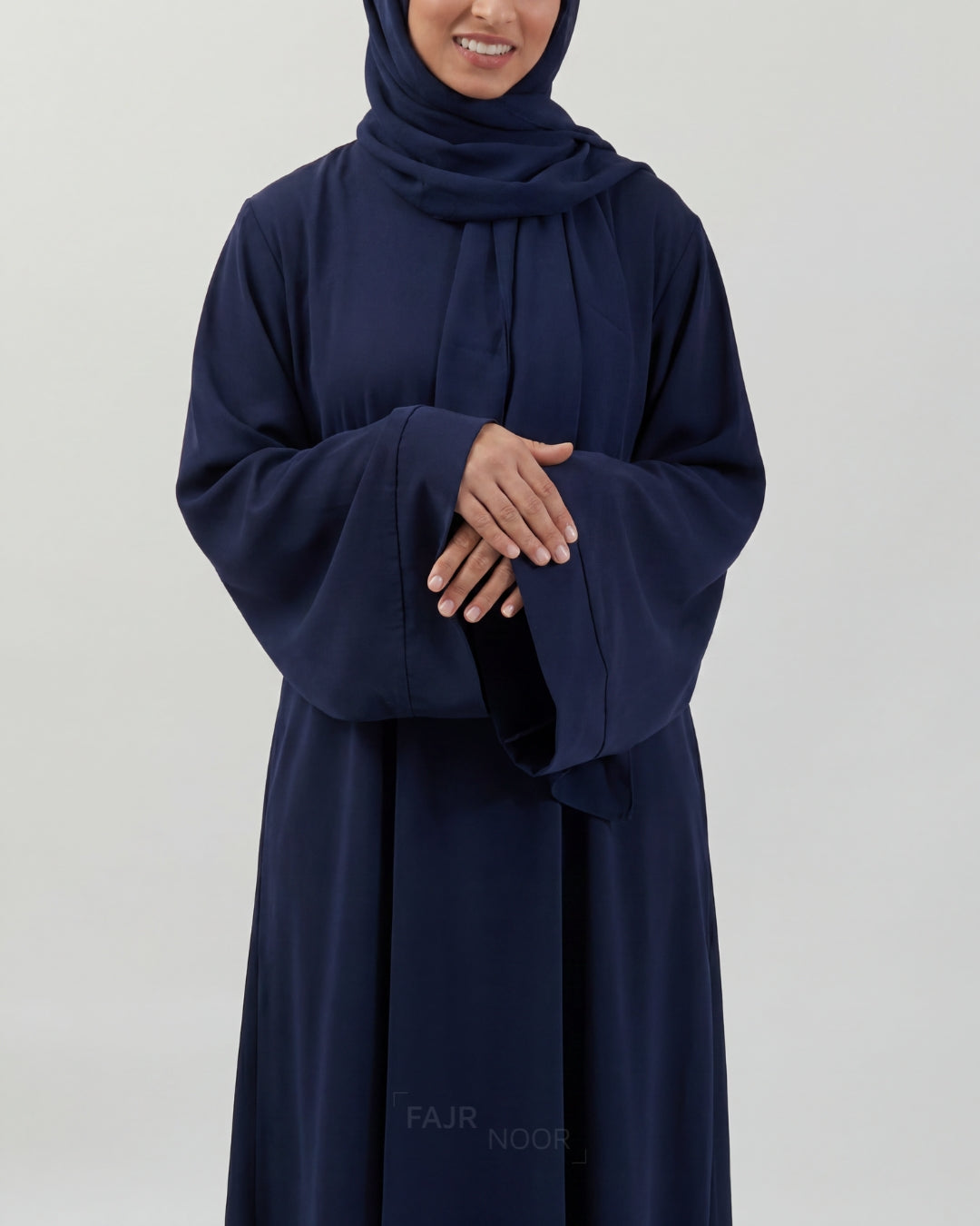 Person wearing a navy blue abaya with a hijab on a white background