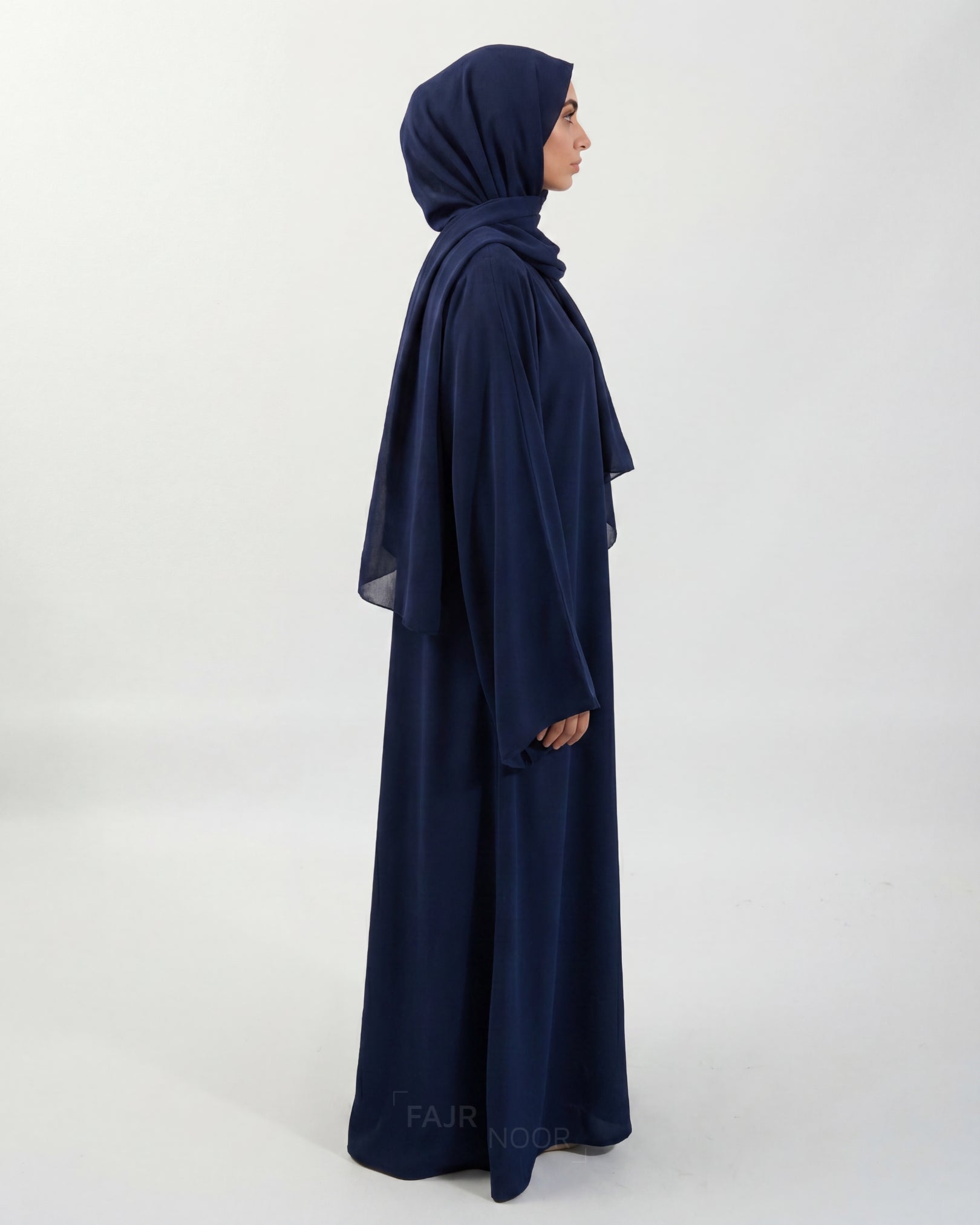 Woman wearing a navy blue abaya and hijab on a white background