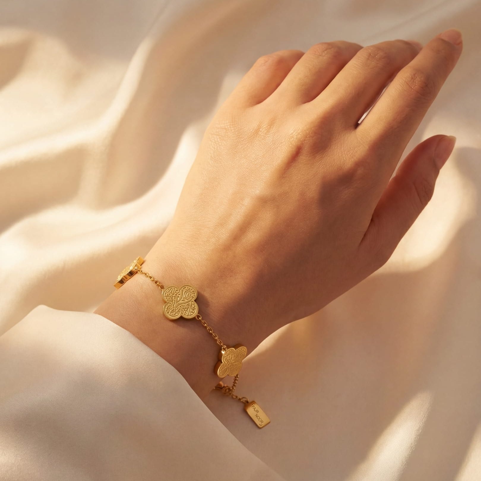Gold bracelet on a hand against a soft beige background