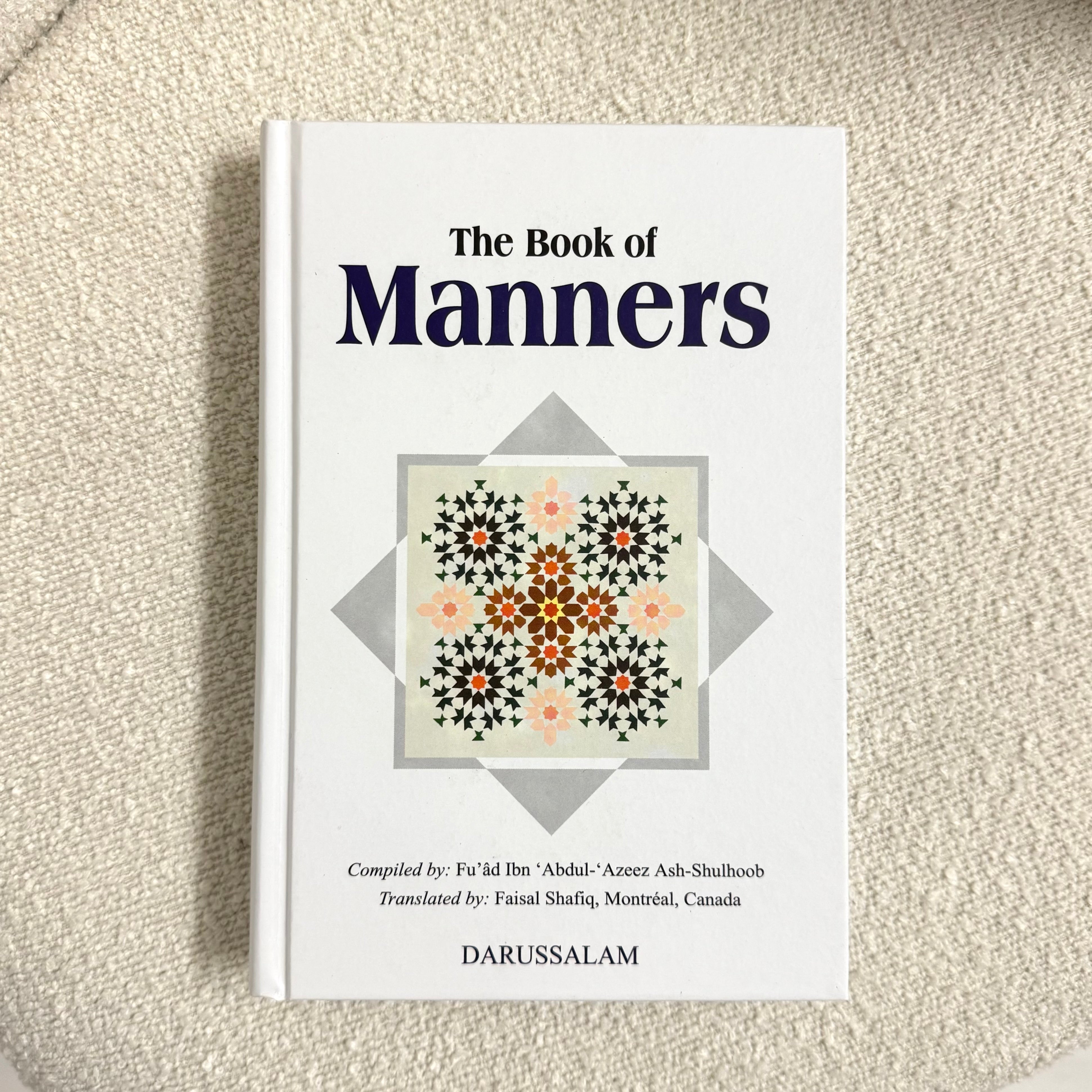 Book titled 'The Book of Manners' on a textured surface