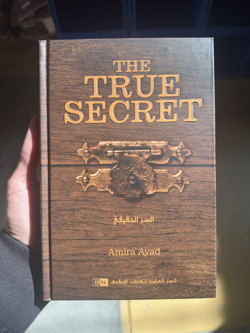 Book titled 'The True Secret' by Amira Ayad held by a person.