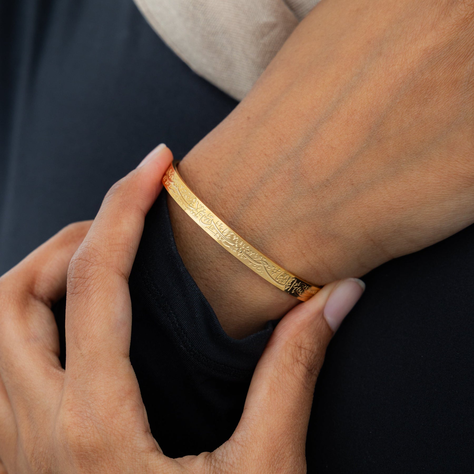 Gold bracelet being worn on a wrist with a blurred background
