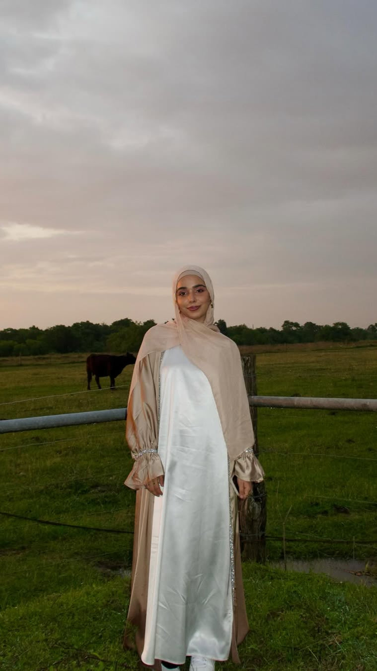 Woman standing in a field with cows under a cloudy sky