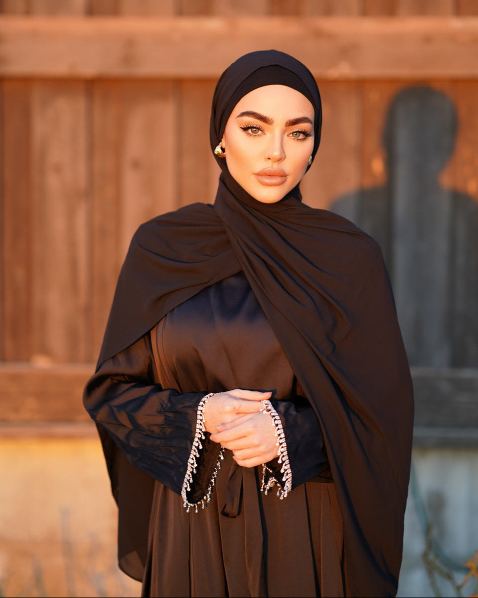 Woman wearing a brown traditional outfit with a headscarf against a wooden background
