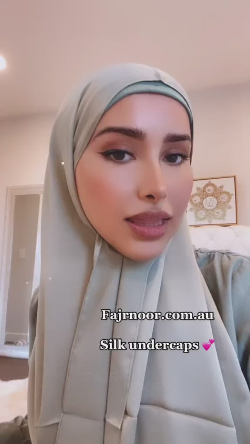 Woman wearing a sage green hijab over a Fajr Noor silk undercap, demonstrating the silk hijab cap underneath