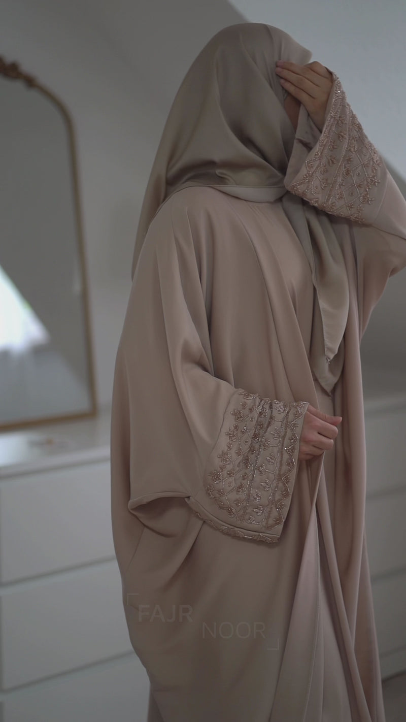 Woman wearing the Fajr Noor Maryam Abaya in cream with embellished sleeve cuffs and a matching hijab