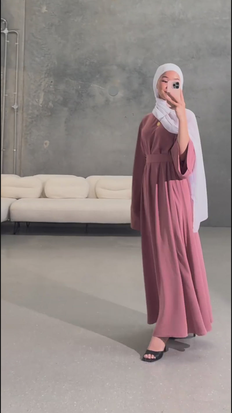 Woman wearing the Fajr Noor Khatijah Abaya in pink with a white hijab, taking a mirror selfie