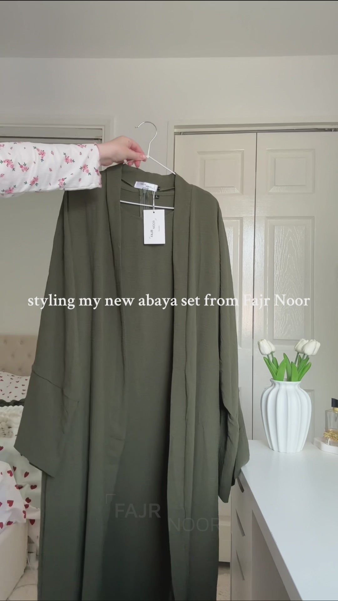 Khaki green Fajr Noor crinkle abaya on a hanger, styled with a Palestine keffiyeh pendant necklace