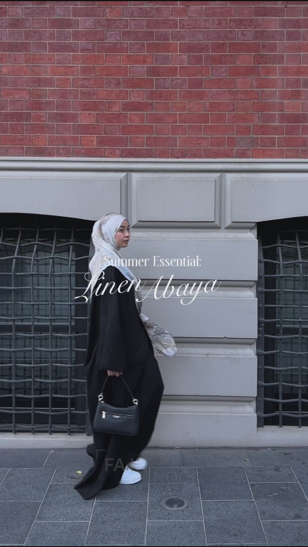 Woman wearing the Fajr Noor Aya Linen Abaya in black with a white hijab, walking outdoors as a summer essential