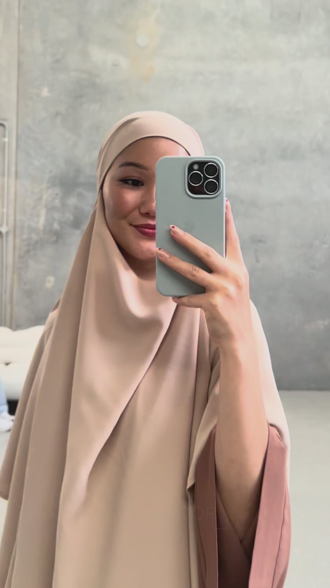 Woman wearing the Fajr Noor Khatijah Abaya in brown with matching hijab, taking a mirror selfie