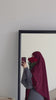 Woman wearing the Fajr Noor Khatijah Abaya in charcoal with a maroon khimar, holding red roses in a mirror selfie