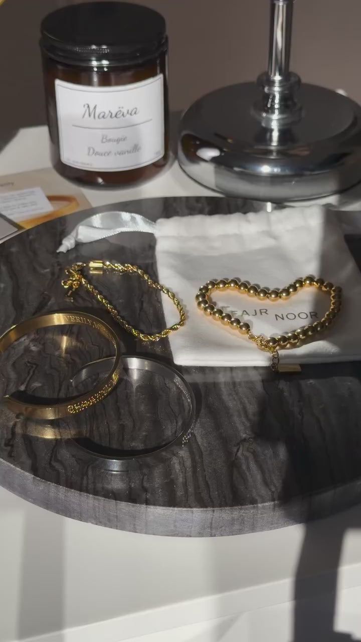 Fajr Noor heart-shaped beaded bracelet displayed on a vanity flat lay with candles and photos