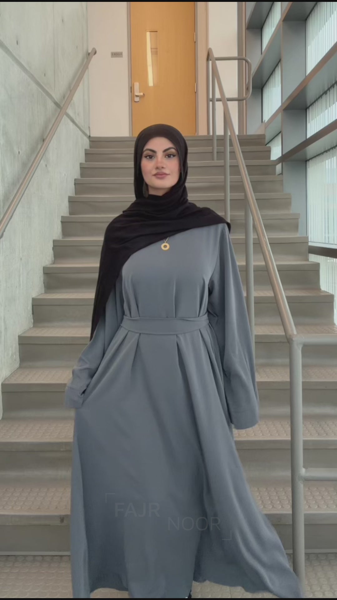 Woman wearing the Fajr Noor Khatijah Abaya in charcoal with a black hijab, showing the belted A-line silhouette