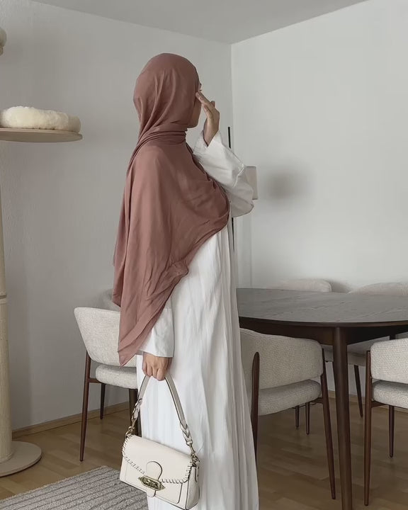 faceless hijabi woman wearing white linen abaya and showing off her outfit