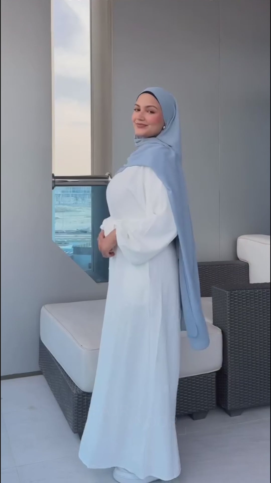 Woman showcasing the Fajr Noor Khatijah Abaya in maroon and emerald with chiffon hijabs, outdoors on a balcony