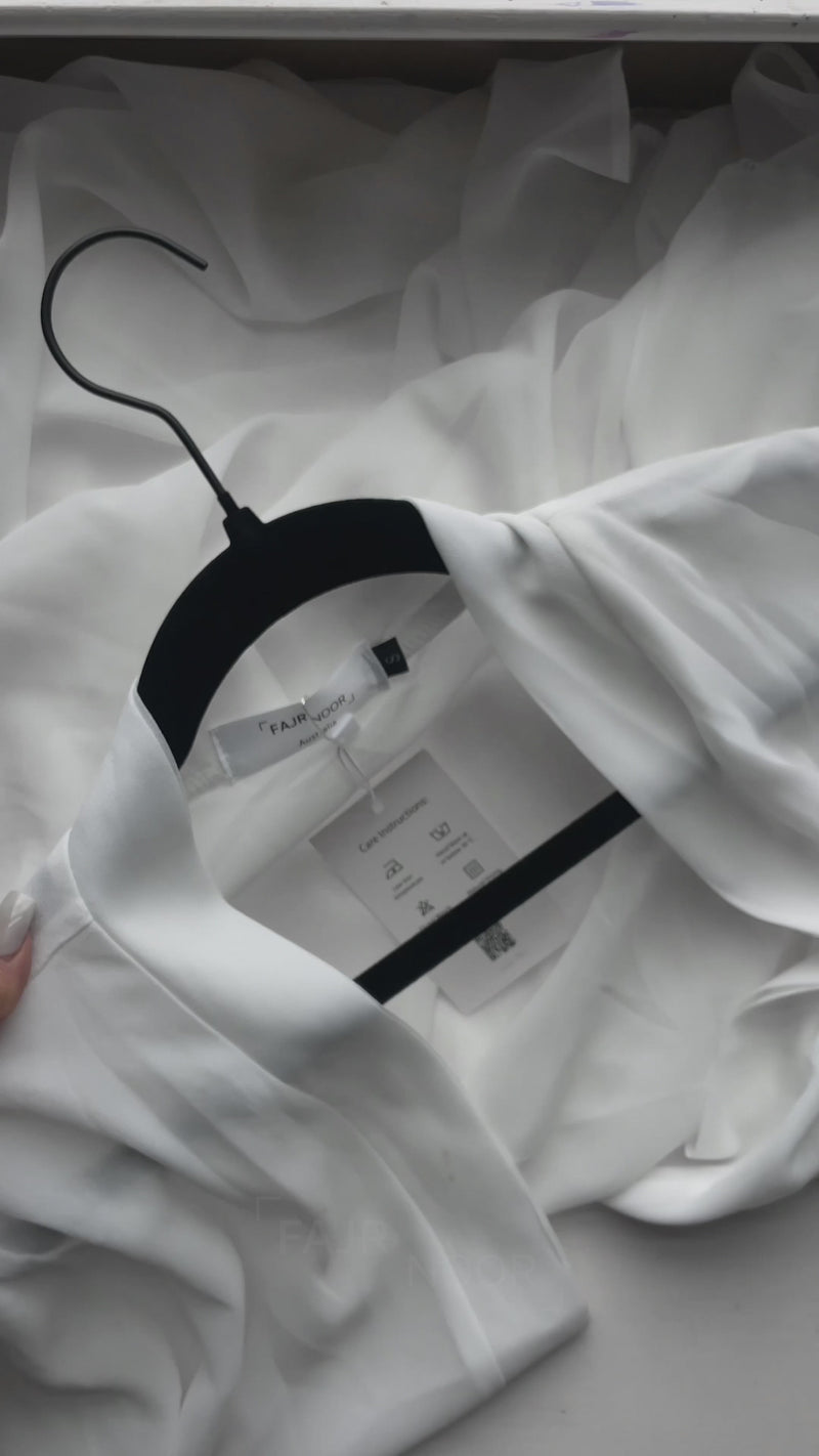 The Fajr Noor Aisha Abaya in white on a hanger, showing the delicate beaded trim detail