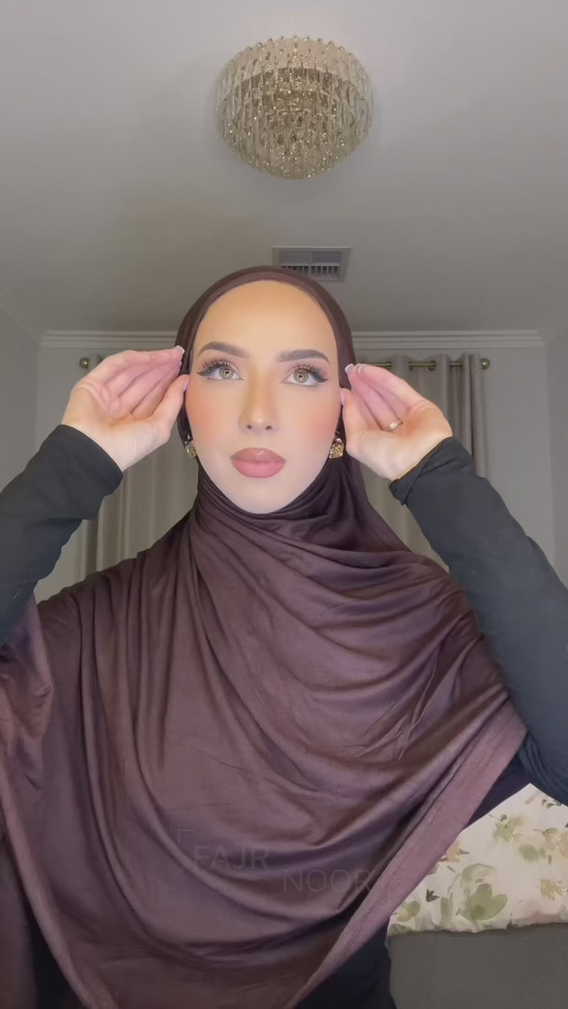 Close-up of a woman wearing a chocolate brown Fajr Noor premium modal hijab, draped and wrapped around her face and shoulders