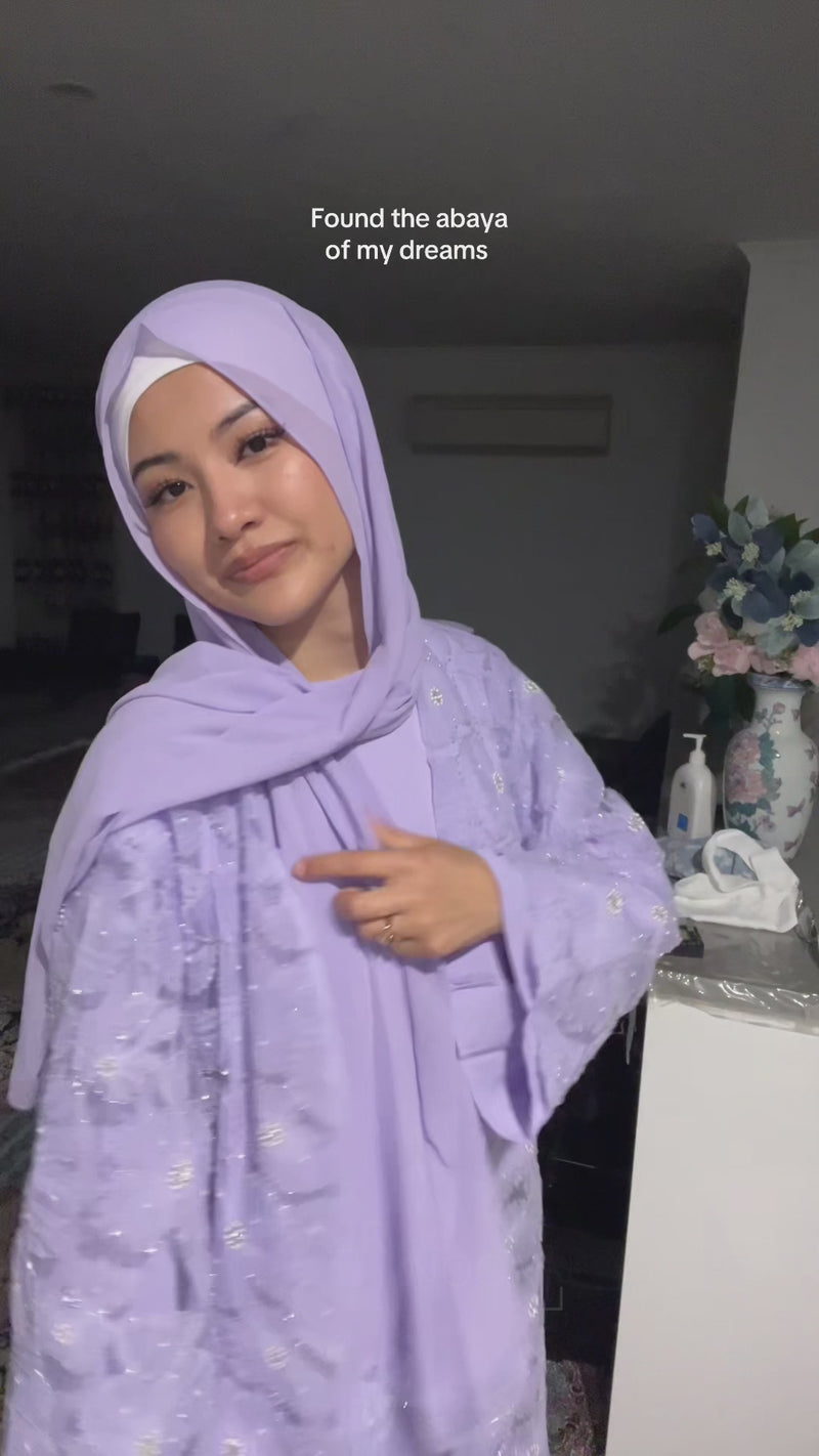 Woman wearing the Fajr Noor Sumayya Abaya in lavender purple with embroidered floral detail and matching hijab