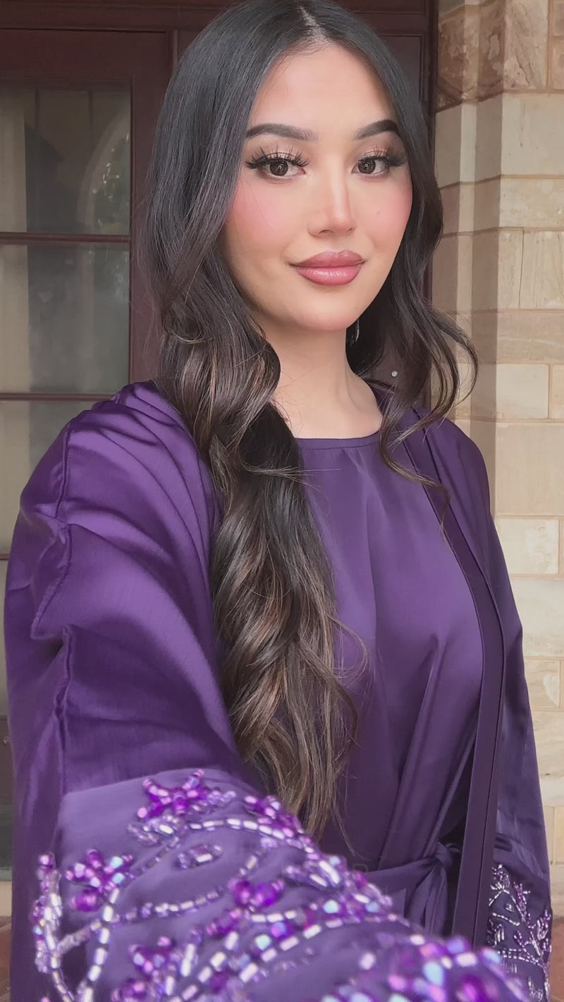 Woman wearing the Fajr Noor Maryam Abaya in purple satin with embellished detailing